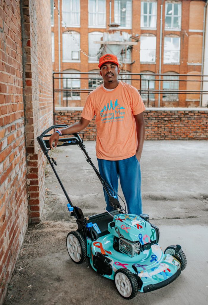 Rodney Smith Jr. standing with lawnmower